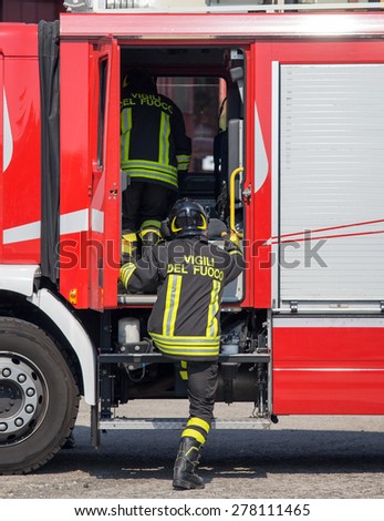 Italian firefighters climb on the trucks of firefighters during an emergency
