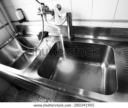 industrial sink with the water tap opened in restaurant
