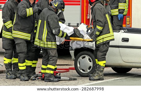 wounded person carried by firefighters on a stretcher after the road accident