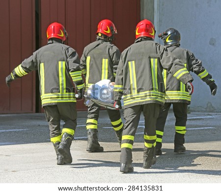 four italian firefighters carry a stretcher with injured