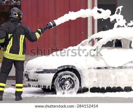 firemen during exercise to extinguish a fire in a car with foam