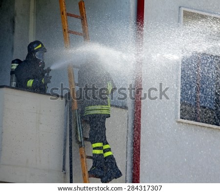 Firefighter sprays water with the spear fighting during the exercise in the firehouse