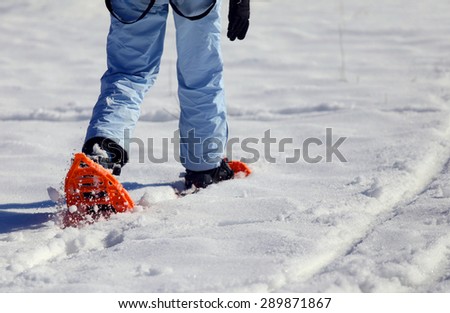 girl walking with snowshoes in mountains in winter