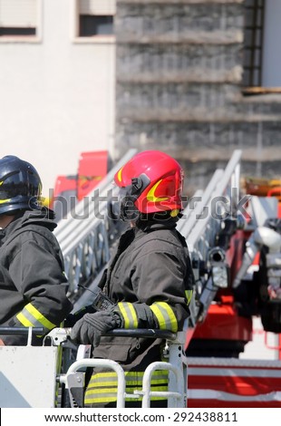 firefighter in the cage of fire engine with red helmet
