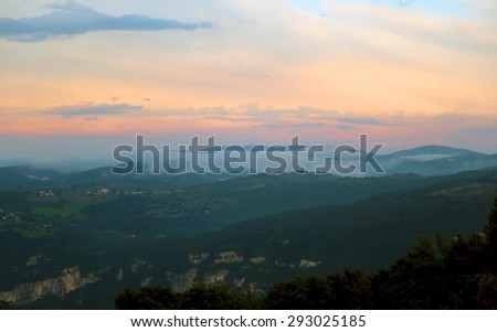 mountains and peaks with the blue light filters between the orange clouds at sunset