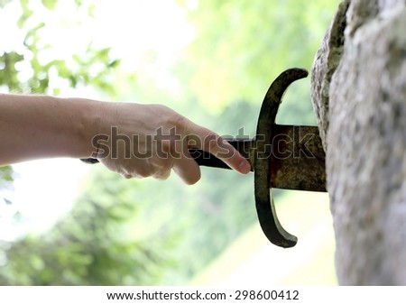 adult hand try to pull the sword in the stone