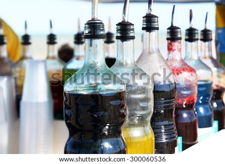 many bottles of colored syrup for preparing ice creams on the beach