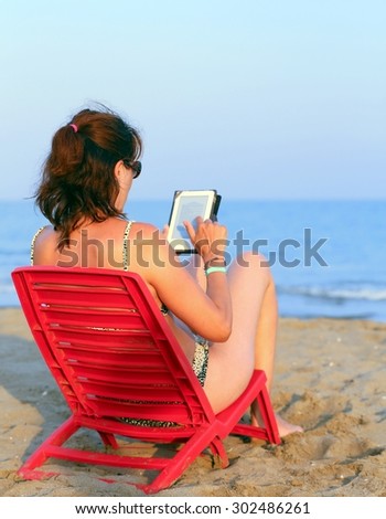 woman reads the ebook on the beach by the sea