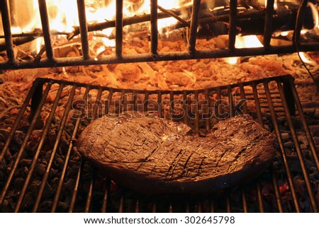 beef steak cooked on the barbeque fireplace with flame