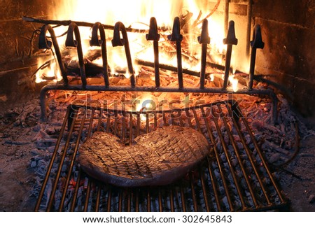 huge beef steak cooked on the barbeque fireplace with flame