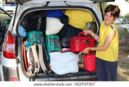 child loads bags in the baggage car in summer