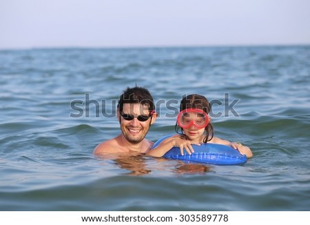 young dad with daughter with the mask to the sea in summer
