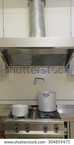 large industrial kitchen cooker with aluminum pots and the giant Exhaust hood