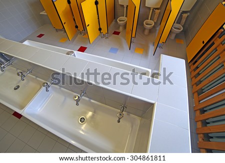 ceramic toilets and small sinks in the bathroom of the kindergarten