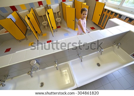 little girl is washing her hands in the bathroom of the school