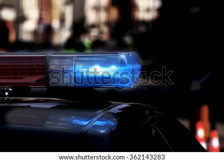 Police patrol car with flashing lights and siren on during the night raid against crime