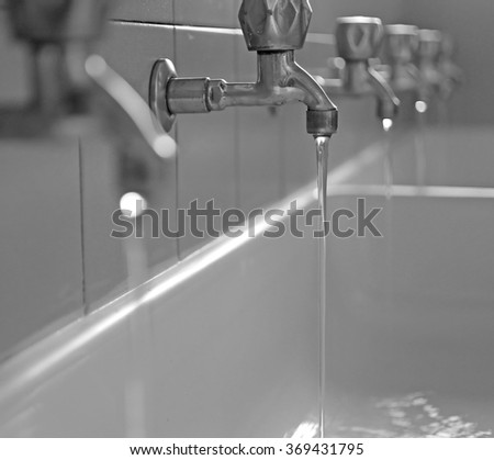 series of stainless steel taps with water coming out of the school in the sink