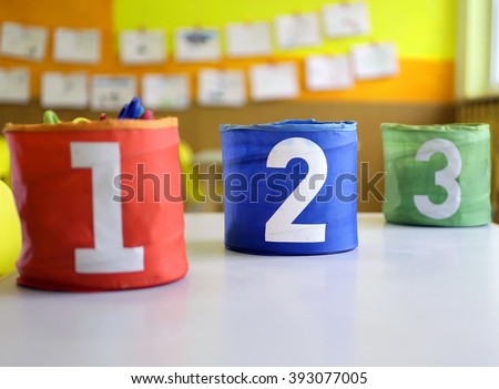 Red Green blue jars with large lettering one two and three on the table in the kindergarten class
