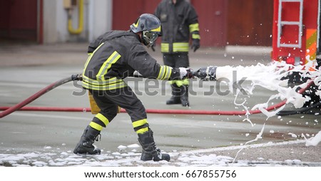 Firefighters while extinguishing the fire with a special fire extinguishing equipment with foma