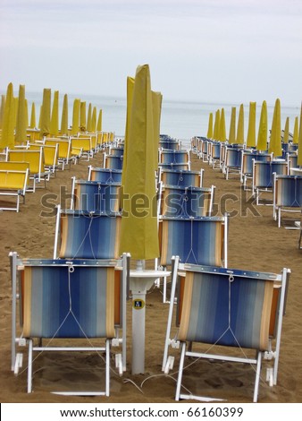 sun beds and umbrellas closed in a deserted sandy beach in an Italian sea