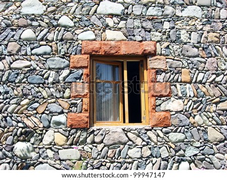 open window surrounded by a wall of rocks and stones