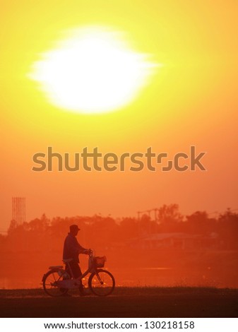 An old man with bicycle in sunset