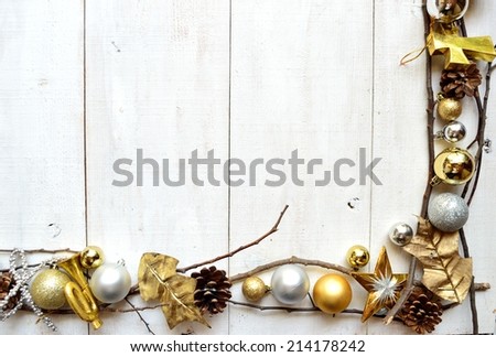 Gold and silver Christmas ornaments on white wooden background.