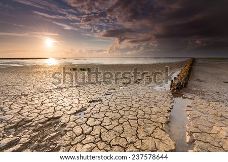 Sunset with low tide at the Wadden sea. Soil is showing some footprints.