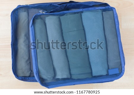 Cube meshed bags with rolled clothes, t-shirt, pants. Set of travel organizer to help packing luggage easy, well organized