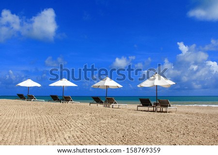 Sunbathing Beds with White Umbrella along the tropical beach