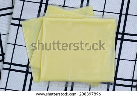 Processed Cheddar Cheese in individual wrapped slides, on a checked cloth