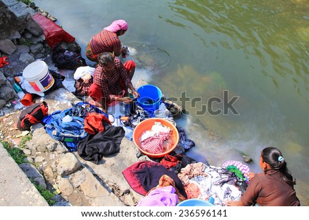POKHARA, NEPAL - APRIL 15 : Nepalese women washing clothes along the river on 15 April 2014 in Pokhara city, Nepal.