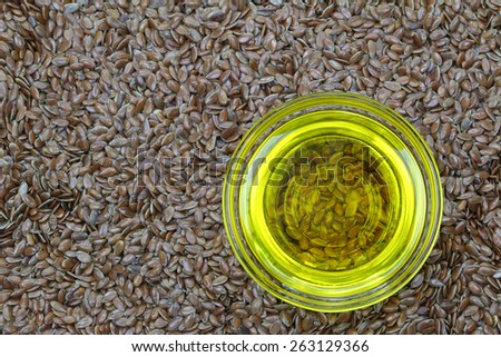 A bowl of cold pressed Linseed yellow oil on flaxseed background. flaxseed are seeds from flax plant