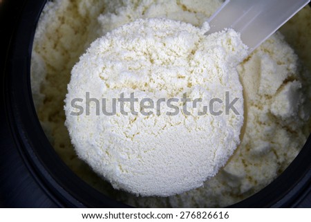 A scoop of fine Whey Protein Isolate Pure powder in a container