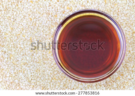 A bowl of cold pressed Sesame oil on white sesame seeds background