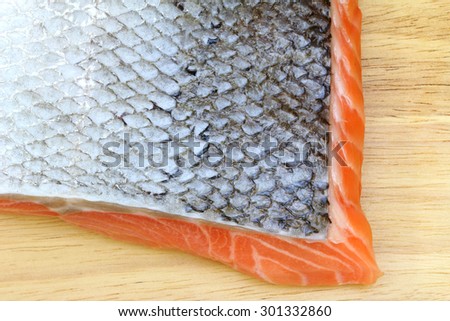Closeup photo of Raw salmon with skin on wooden cutting board