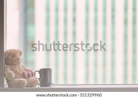 A bear sitting next to the window with a coffee mug with vintage filter