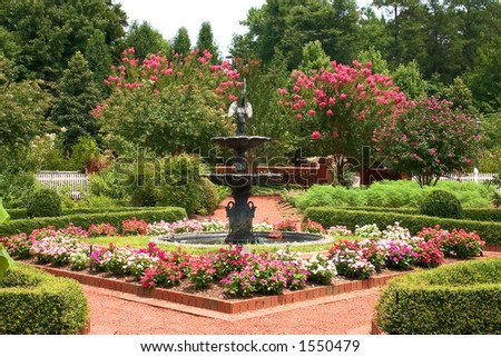 Formal garden with fountain in center and bright flowers *web use*