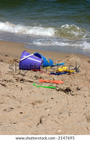 Beach toys on shore with breaking waves, vertical