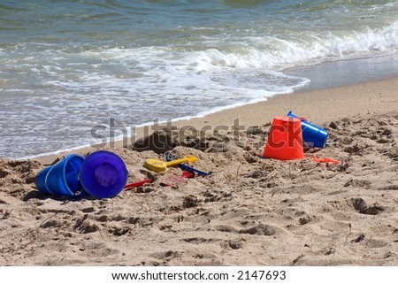 Beach toys on shore with breaking waves, horizontal