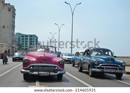 Havana - July 18: American classic cars driving along the famous Malecon coast road in Havana, Cuba on July 18, 2014. Classic car rides are a popular tourist activity in Havana.