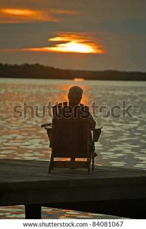 elderly person sitting alone in chair looking at sunset