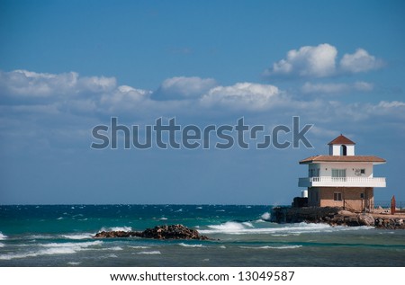 White building on the sea cost, waves rocks and surf board