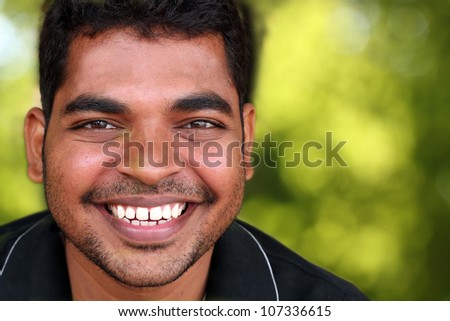 Photo of happy lively handsome middle-aged Indian/asian youth laughing and having fun. The eyebrows are thick and prominent and hair is black and curly with unshaven stubble on the face.