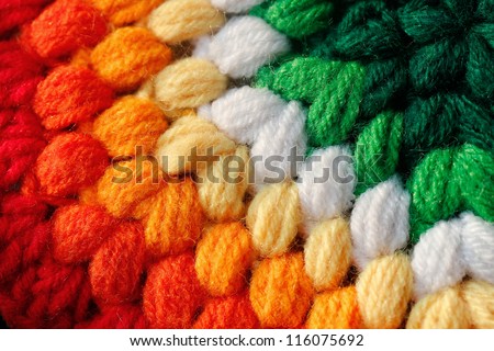 Beautiful colorful handmade woolen fabric closeup photo. The colors of the cloth include red, orange, yellow, green and pink.