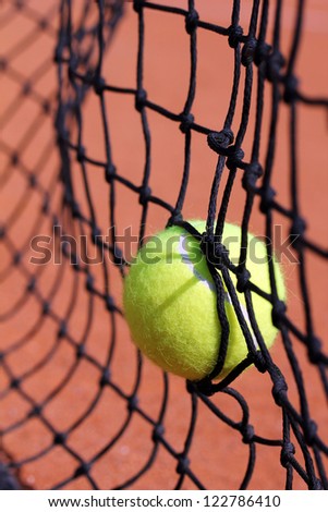 Photo of new tennis ball struck in tenis net on a clay court