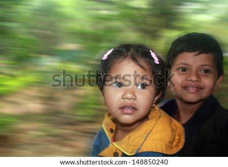brother & sister having fun in a moving toy train. The photo shows 2 happy indian kids, a girl & a boy, sitting together in a fast moving train and enjoying their time