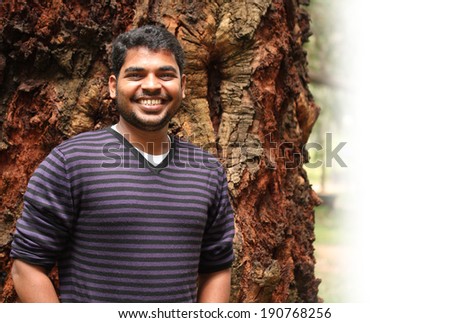Young indian adult smiling looking at camera and expressing joy and happiness. The photo is with space for text on the right.