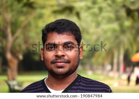 healthy cheerful indian adult entrepreneur relaxed on a sunny day in a garden with blurry green leaves in the background