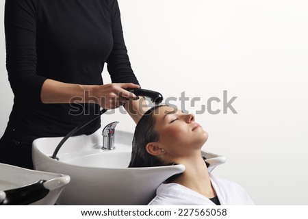 beautiful young woman getting a hair washed by hairdresser at salon